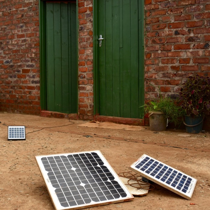 A trio of medium-sized solar panels strategically placed outside the doors of several homes sharing a courtyard.